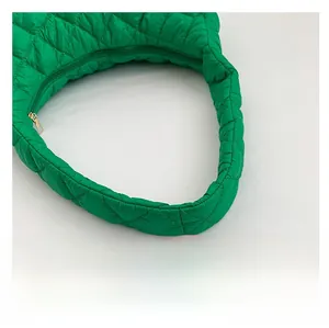 Detailed view of the green quilted nylon fabric and secure metal zipper on the shoulder bag