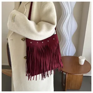 Close-up of wine red bohemian tassel shoulder bag on a model wearing an ivory wool coat