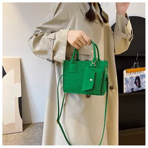 Detailed close-up of green embossed felt handbag featuring a detachable mini coin purse