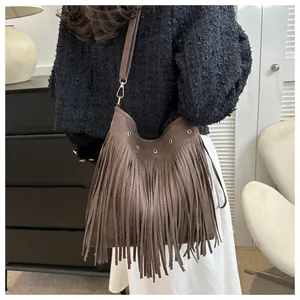 Detail of brown faux suede tassel shoulder bag showing long fringe and silver metal eyelets