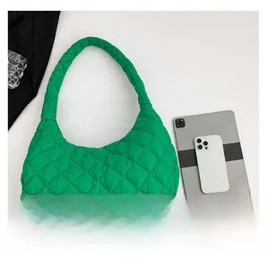 Quilted green puffy shoulder bag shown next to a tablet for size comparison