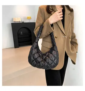 Close-up of black quilted puffer hobo bag with glossy finish on model's shoulder
