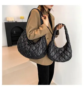 Macro detail of black quilted cloud bags in two sizes worn by a model in a beige suit