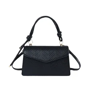 Borsa a mano nera minimalista con trama intrecciata, dettagli oro e manico a nodo