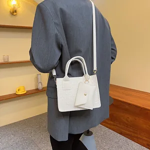 White embossed tote bag with a small coin purse shown on a model in a grey suit