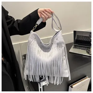 Close-up of light gray suede tassel bag with metal eyelets and long fringe detail
