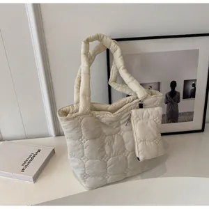 Dettaglio di una borsa tote trapuntata color crema con trama a bolle e mini portamonete