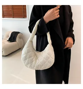 Close-up of cream quilted moon bag with large diamond stitching on model with black coat