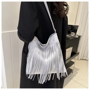 Detail of light gray bohemian tassel shoulder bag with silver rivet studs and suede texture