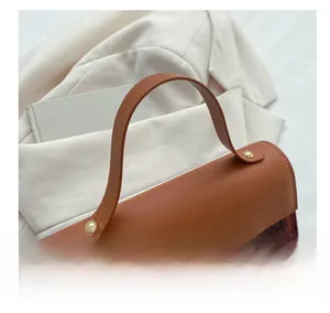 Detail view of stylish brown leather handbag with red and green plaid fabric patchwork