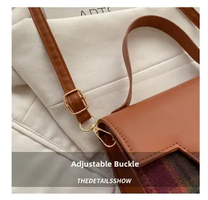 Detail of adjustable metal buckle and red-green plaid fabric on vintage shoulder bag