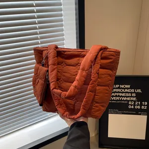 Dettaglio della borsa tote imbottita color caramello con pochette e catena abbinata
