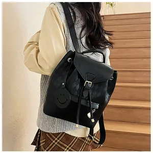 Détail du tissage et du pendentif smiley sur un sac à dos noir en cuir pour femme
