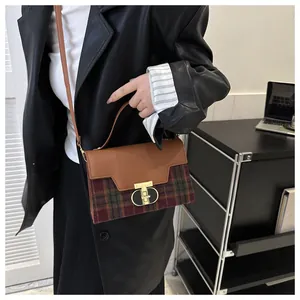 Detail of vintage plaid handbag with leather patchwork and golden T-lock on a model