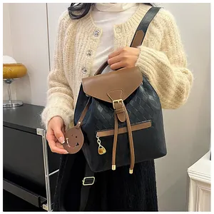 Détail d'un sac à dos en cuir à carreaux avec pendentif cœur doré et porte-clés smiley