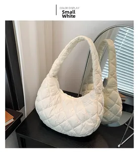 Detail of small white cloud shoulder bag with quilted diamond pattern on black table