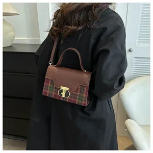 Close-up of retro plaid patchwork handbag featuring a golden round metal twist lock