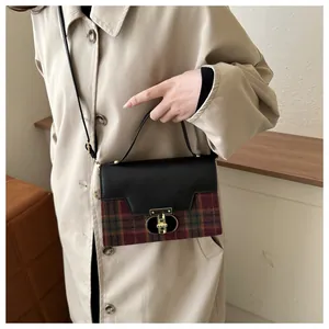 Detail of tartan wool crossbody bag with black leather flap and gold twist-lock closure
