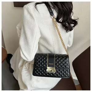 Détail du sac bandoulière noir matelassé avec boucle dorée sur blazer en tweed