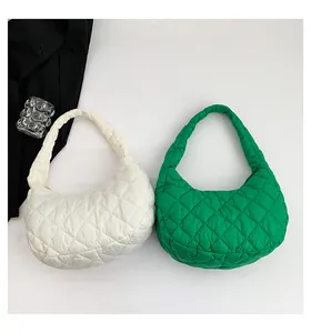 Close-up of quilted cloud-shaped shoulder bags in emerald green and white nylon fabric