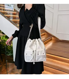 Close-up of white bucket shoulder bag with double pockets and drawstring closure