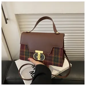 Detail of vintage plaid handbag featuring brown leather trim and golden metal twist lock