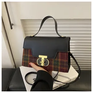 Detail of the vintage plaid handbag featuring leather patchwork and a gold T-lock closure