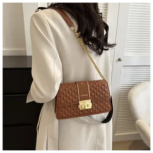 Détail d'un sac bandoulière matelassé marron avec fermoir doré et bandoulière en chaîne
