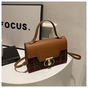 Detail of vintage plaid handbag featuring premium brown leather and gold metal buckle