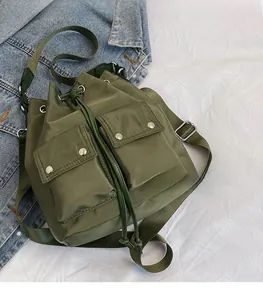 Detail of army green nylon bucket bag with dual front pockets on denim jacket