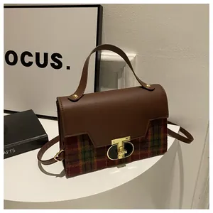 Macro detail of retro plaid patchwork handbag with golden T-shape twist lock and leather