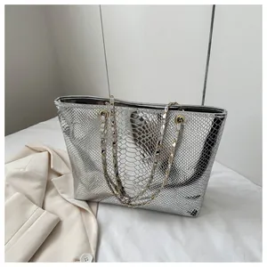 Macro view of silver tote bag featuring faux snake texture and metallic chain handle