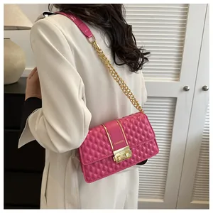 Détail d'un sac carré rose matelassé avec fermoir doré et bandoulière sur le mannequin