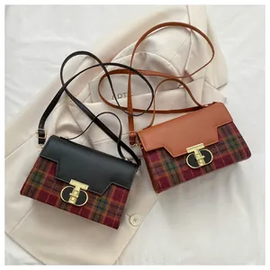 Detail of vintage plaid handbag with a golden T-shaped twist lock on leather flap
