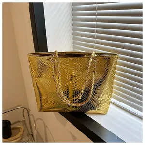 Close-up of metallic gold tote bag featuring detailed snake skin texture and chain strap