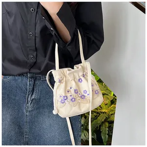 Detail of floral embroidery and delicate lace on beige canvas bucket bag for women