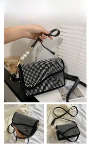 Detail of silver studded crossbody bag with luxury pearl strap and bear metal accent