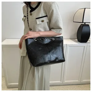 Detailed view of black crocodile pattern leather tote bag with metal chain strap