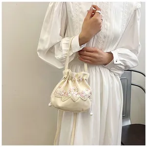 Close-up of hand-embroidered floral patterns and pearl drawstring on the vintage bucket bag