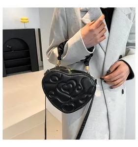 Detail der herzförmigen gesteppten Ledertasche mit goldenen Beschlägen und Rüschengriff