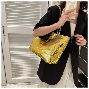 Detail of gold faux leather tote bag with snakeskin texture and metal chain strap