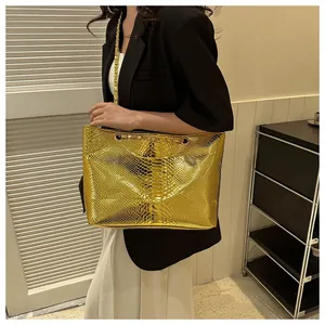 Detail of gold tote bag with embossed snake texture and metallic chain shoulder strap