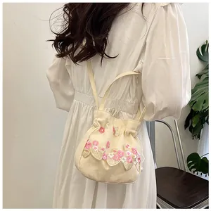 Detail of a handmade lace bucket bag featuring pink floral embroidery on beige canvas