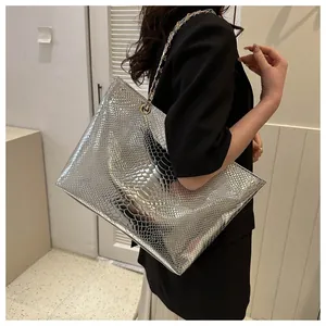 Detailed macro view of silver metallic snakeskin tote bag with woven chain strap