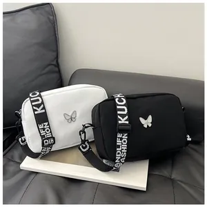 Détail du sac bandoulière en nylon avec décor papillon argenté et large sangle à motif