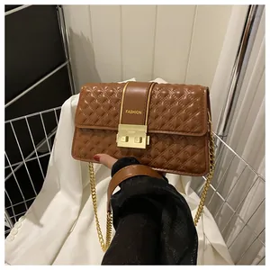 Détail du sac en cuir matelassé marron avec fermoir rotatif doré et bandoulière chaîne