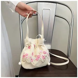 Detailed embroidery and pearl drawstring on cream canvas bucket bag for women