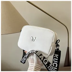 Détail du sac carré blanc en nylon avec boucle papillon argentée et bandoulière large