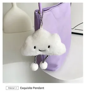 Nahaufnahme eines weißen Plüschwolken-Anhängers mit Lächeln an einer lila Bucket-Bag