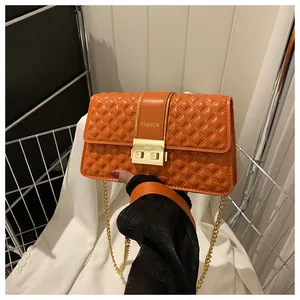 Gros plan du sac bandoulière orange matelassé avec chaîne dorée et boucle métal